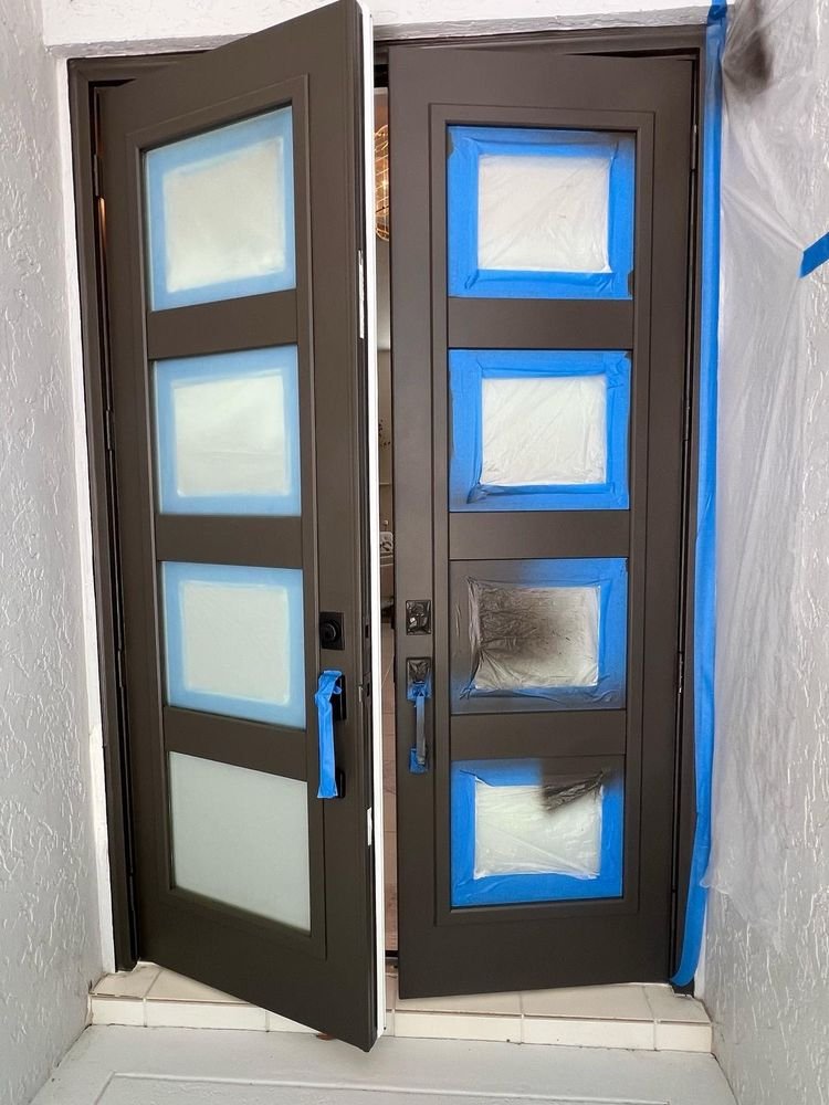 Unmasking tape from fresh dark bronze finish on double exterior doors in Jupiter FL