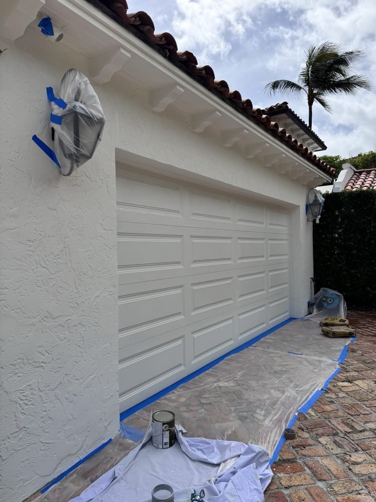 Painted double garage doors and crisp white stucco facade in Jupiter FL